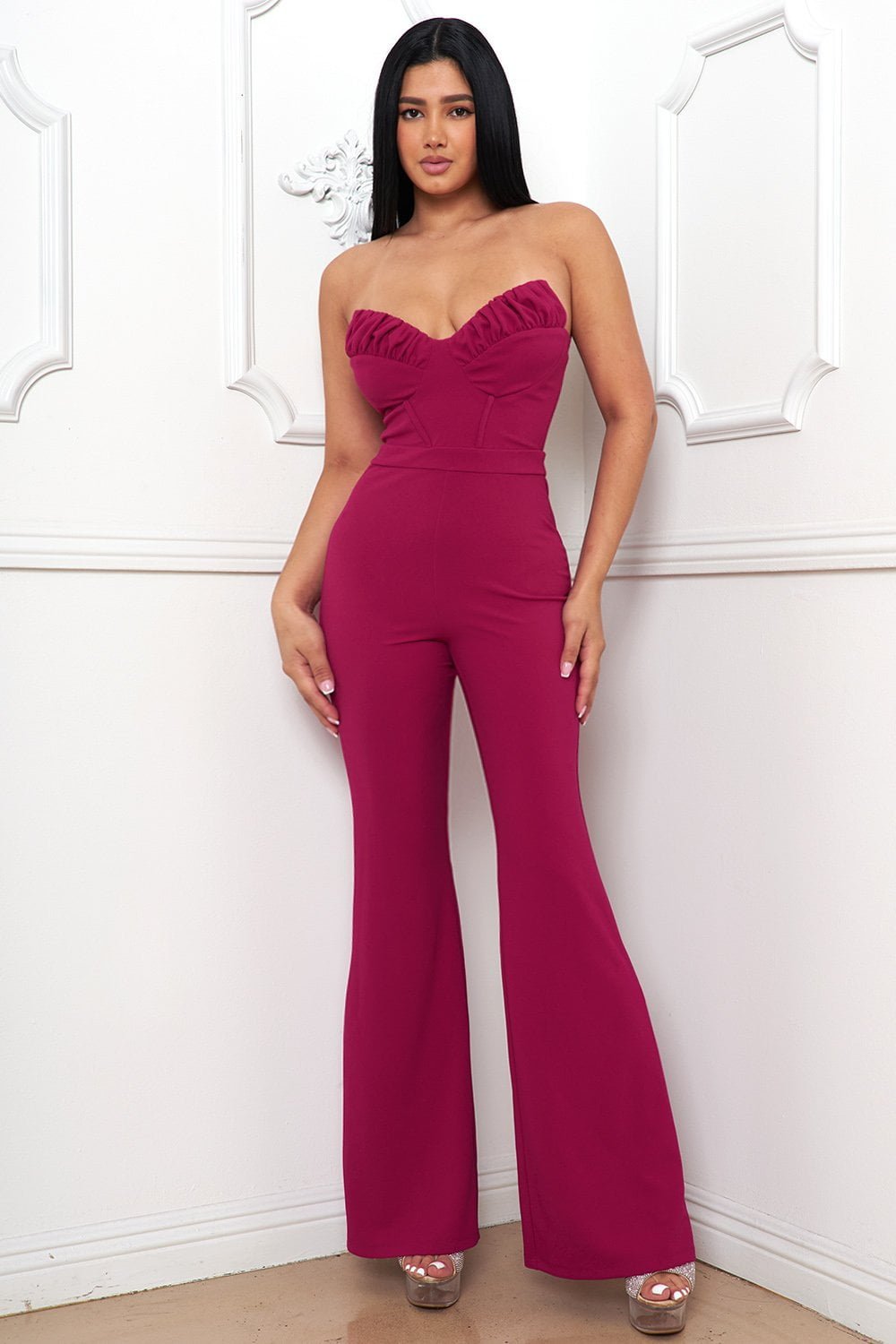 Model wears a chic pink strapless corset jumpsuit with a sweetheart neckline for an elegant evening look.