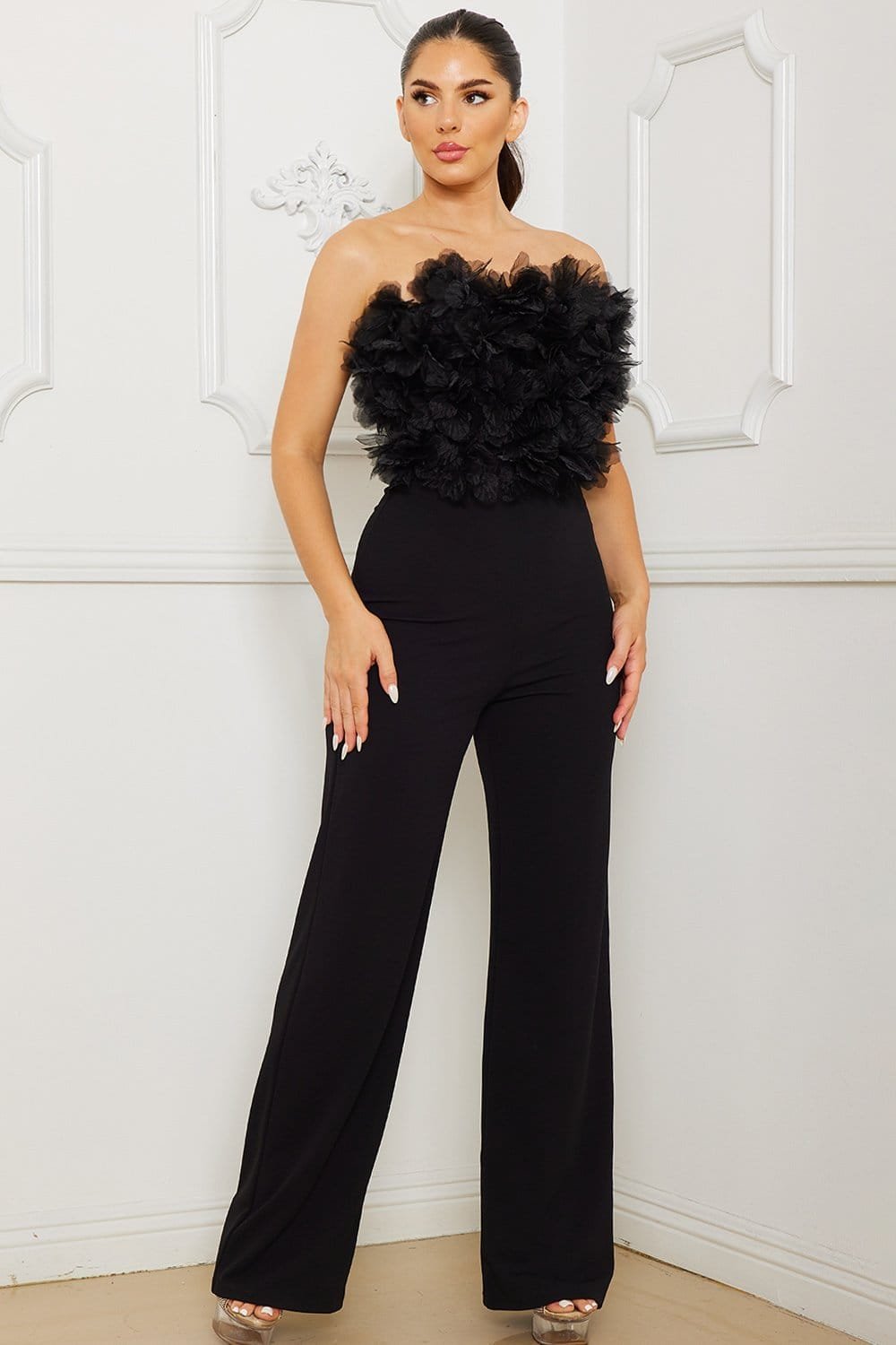 Black strapless jumpsuit with ruffled tulle bodice and wide-leg trousers, perfect for a chic evening occasion.