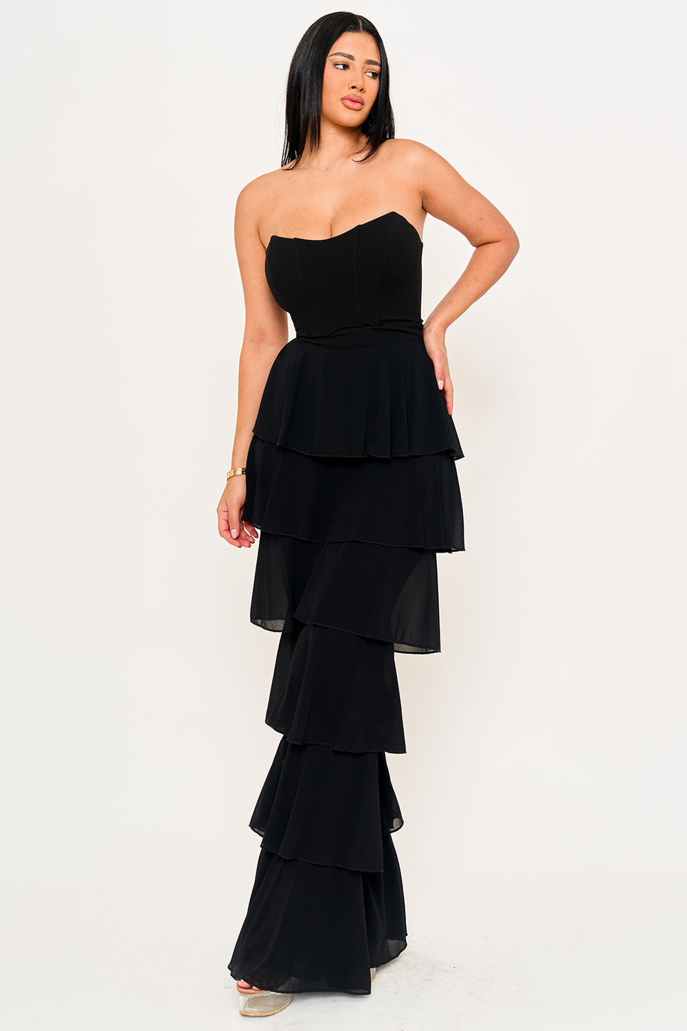 Model wearing a Boutinie black strapless corset-style gown with a tiered chiffon midi skirt for evening occasions.