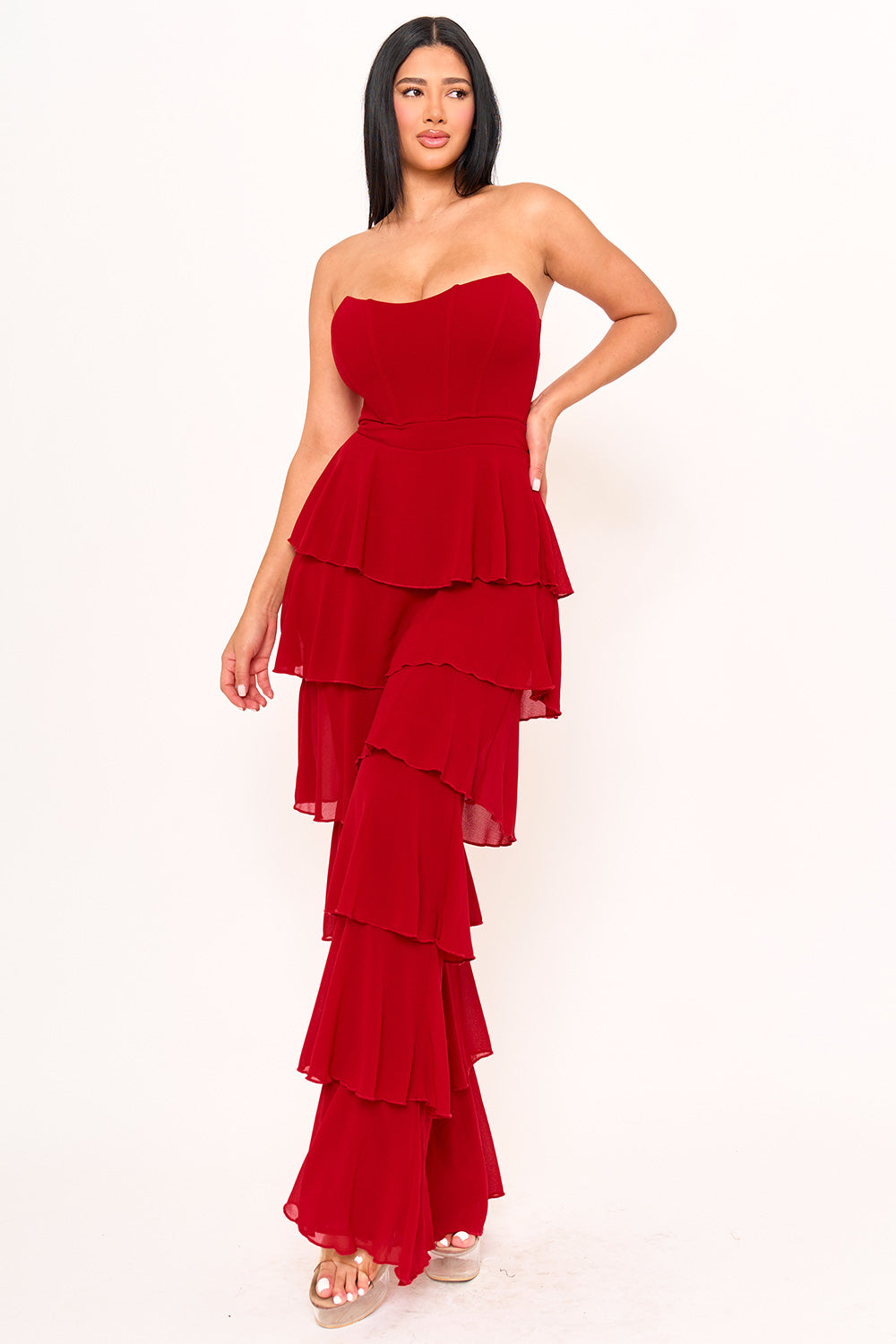 Red strapless jumpsuit by Boutinie featuring a corset bodice and tiered chiffon ruffles for a chic evening look.