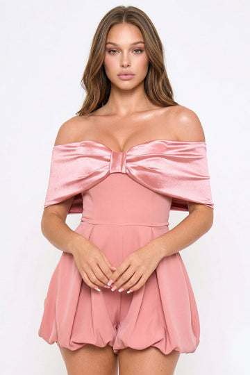 Dusty rose off-the-shoulder party romper featuring a satin bow neckline and a pleated bubble silhouette.