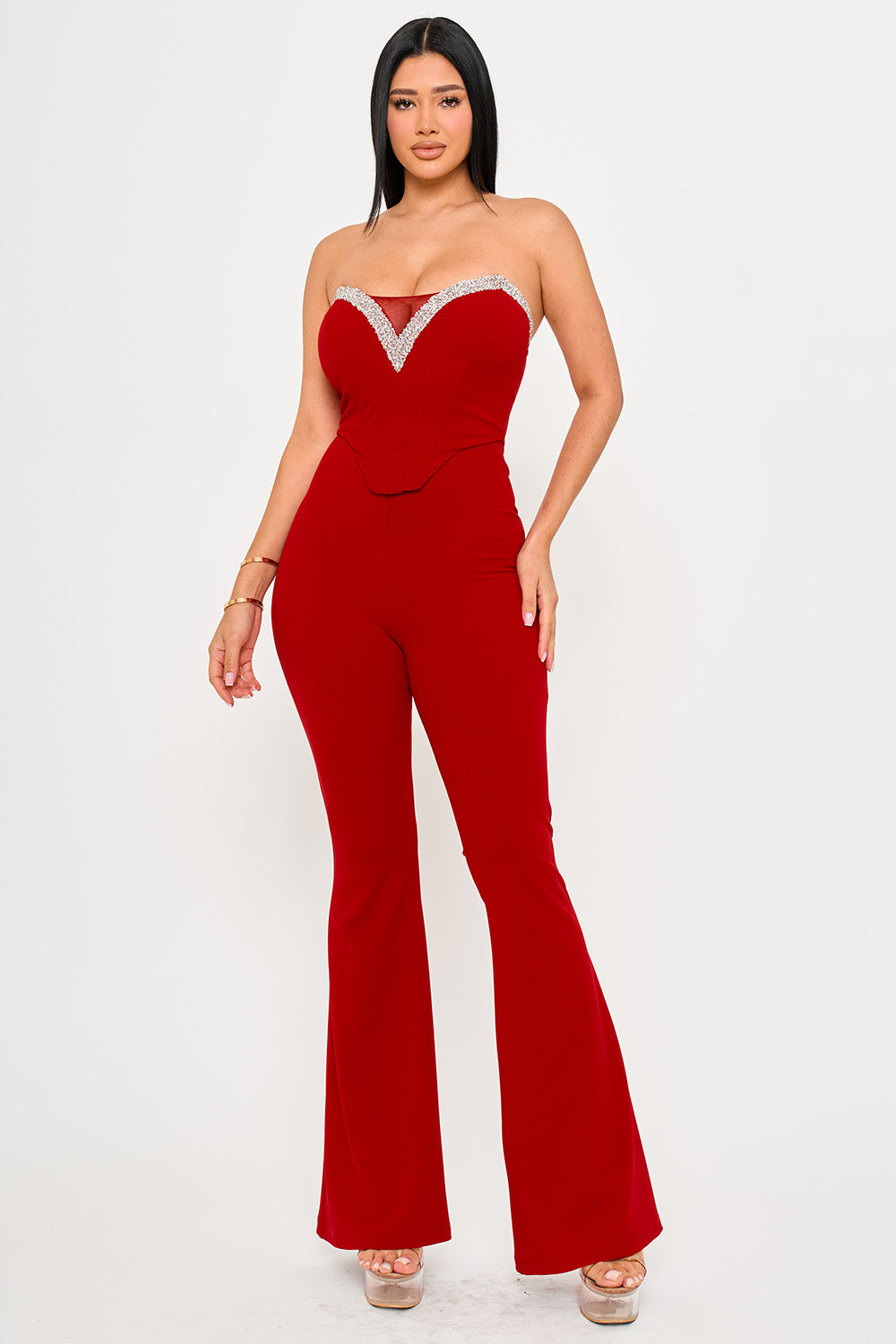 Red strapless corset jumpsuit with rhinestone V-neck detail and flared legs, perfect for a glamorous evening look.