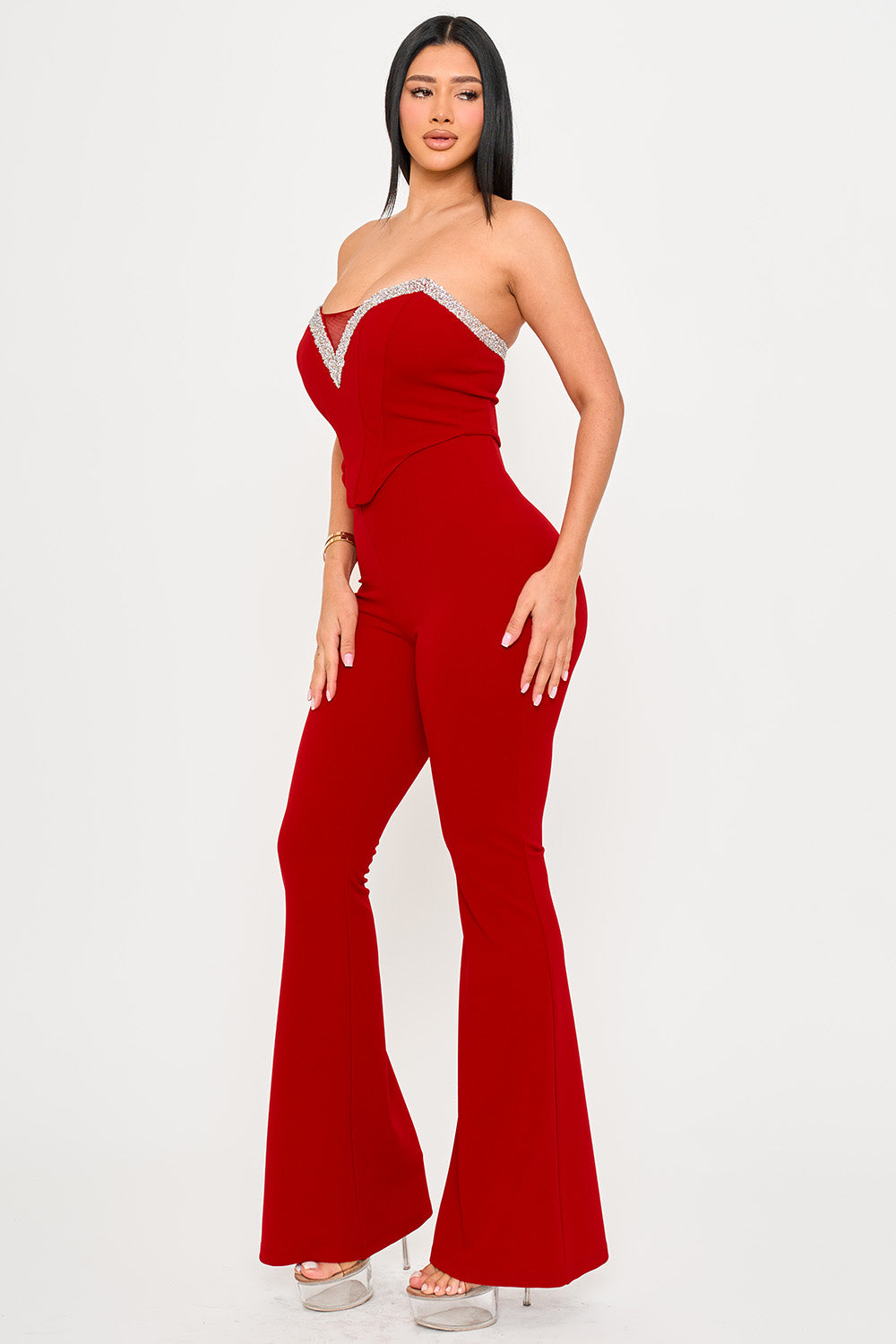 Red strapless jumpsuit with rhinestone trim, sweetheart neckline, and flared legs, perfect for a glamorous evening out.