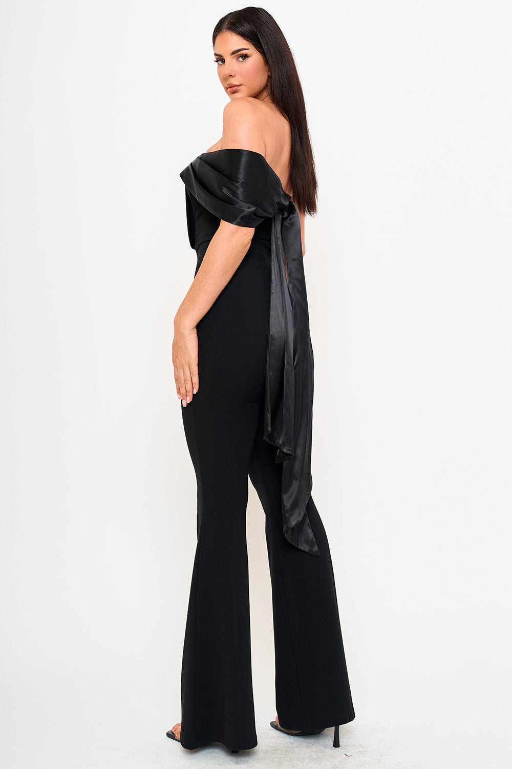 Black off-the-shoulder jumpsuit with satin draping and flared legs, elegant evening wear from Boutinie.