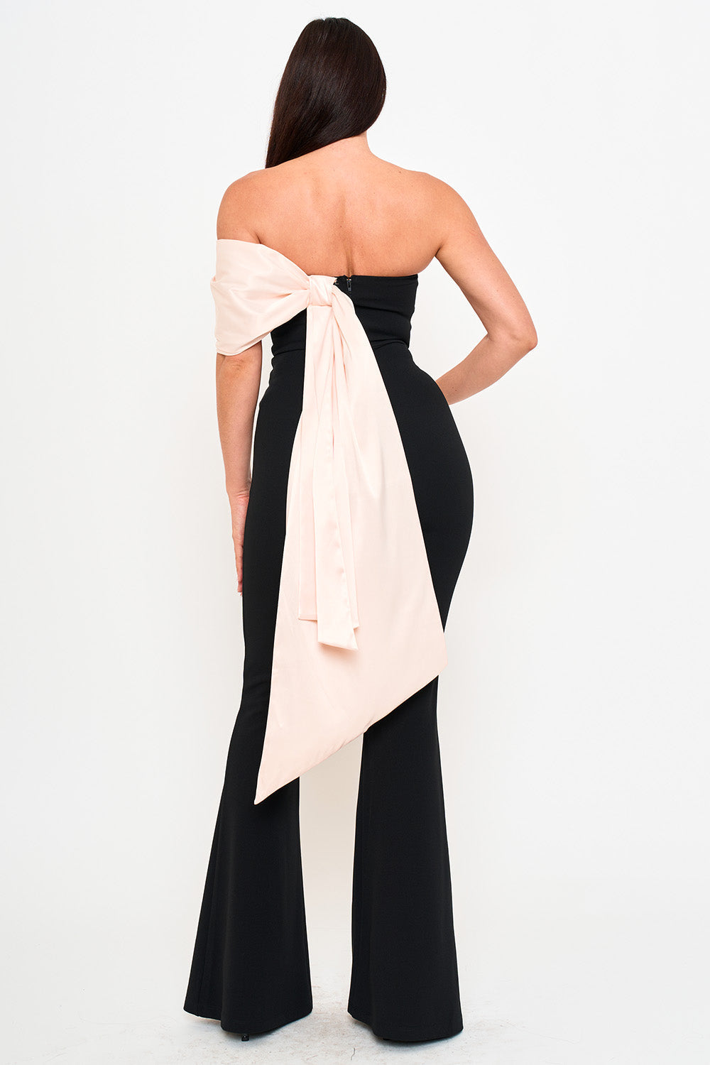 Back view of a black strapless formal jumpsuit with a pale pink satin bow detail by Boutinie.