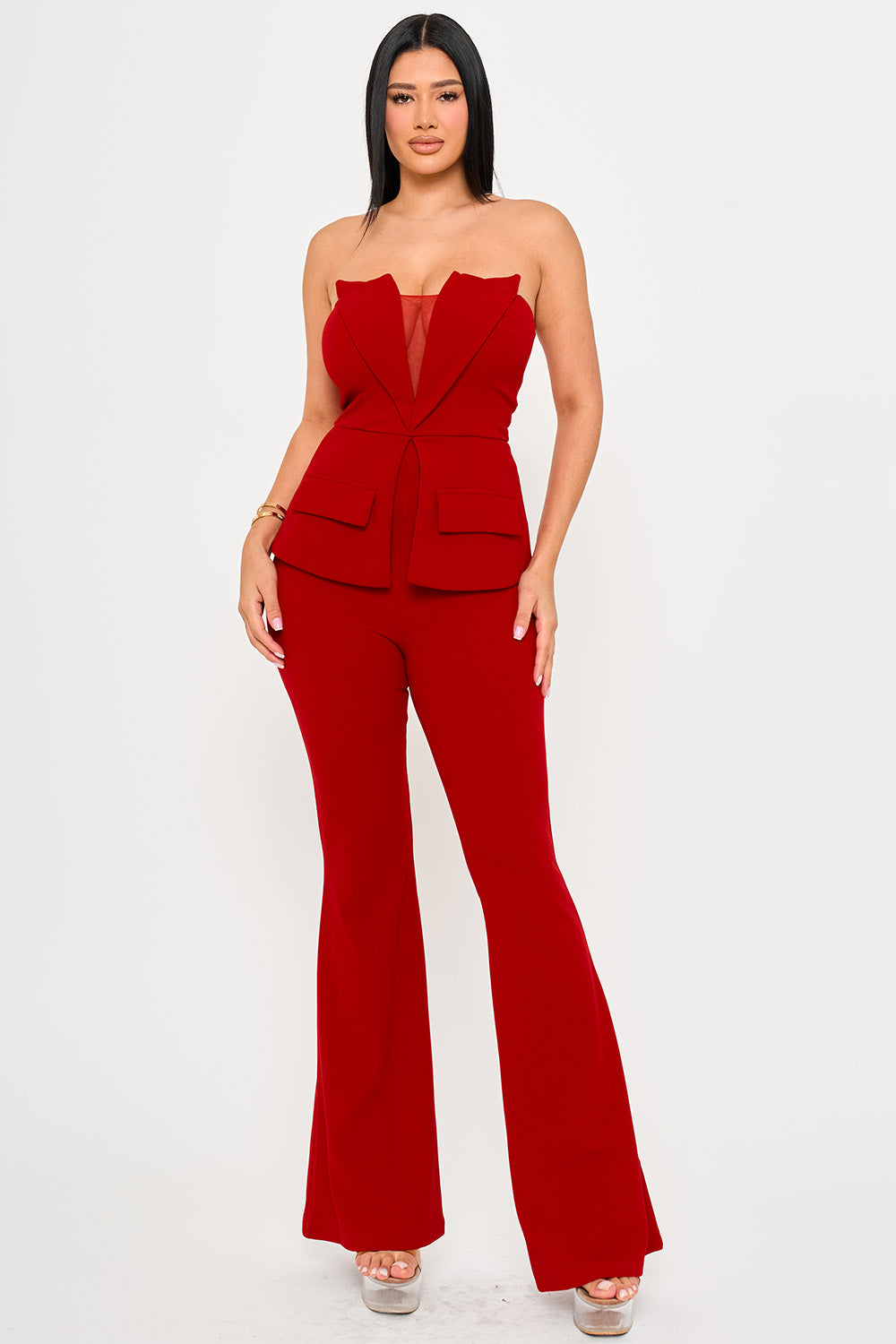 Model wears a red strapless jumpsuit with a blazer-style bodice, mesh detail, and flared legs for a formal look.