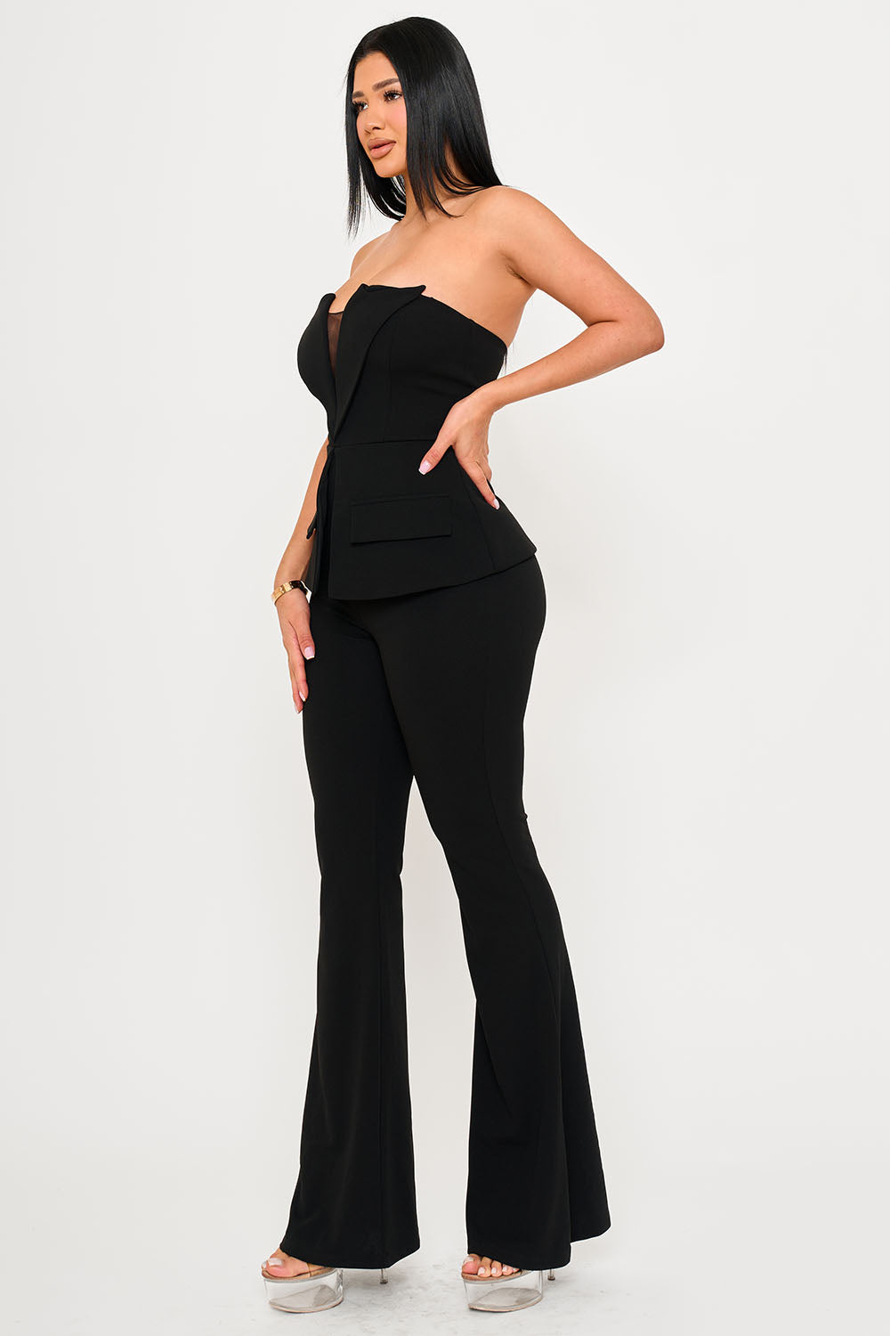 Model wearing a black strapless peplum blazer top and matching flared trousers for a chic evening outfit.