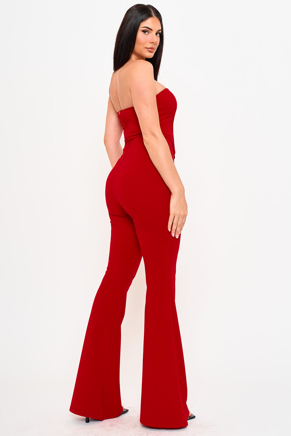 Model wearing a red strapless jumpsuit with a fitted bodice and flared legs, perfect for a chic evening occasion.