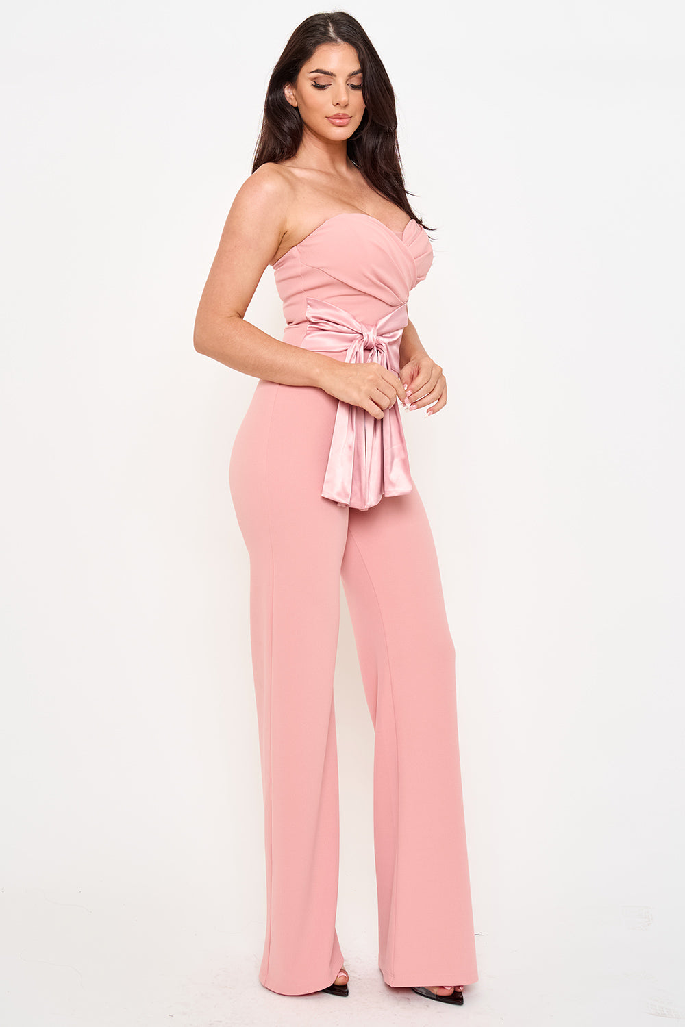 Dusty pink strapless wide-leg jumpsuit with a sweetheart neckline and satin tie-waist detail for formal occasions.