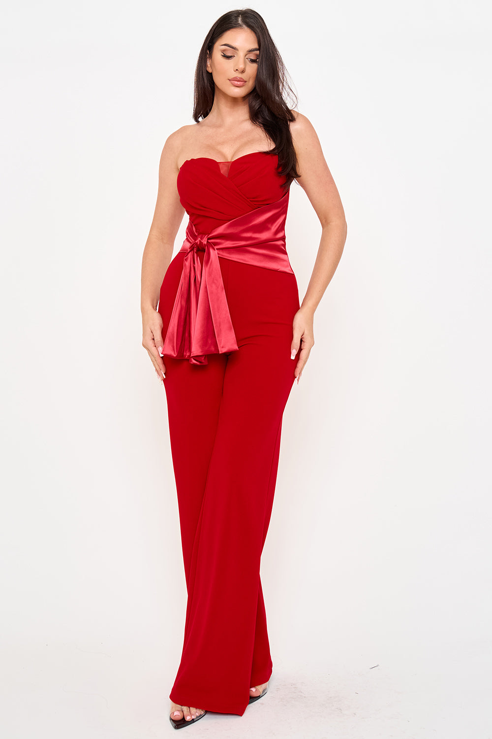 Model in a strapless red evening jumpsuit with a satin tie-waist and wide-leg silhouette from Boutinie.