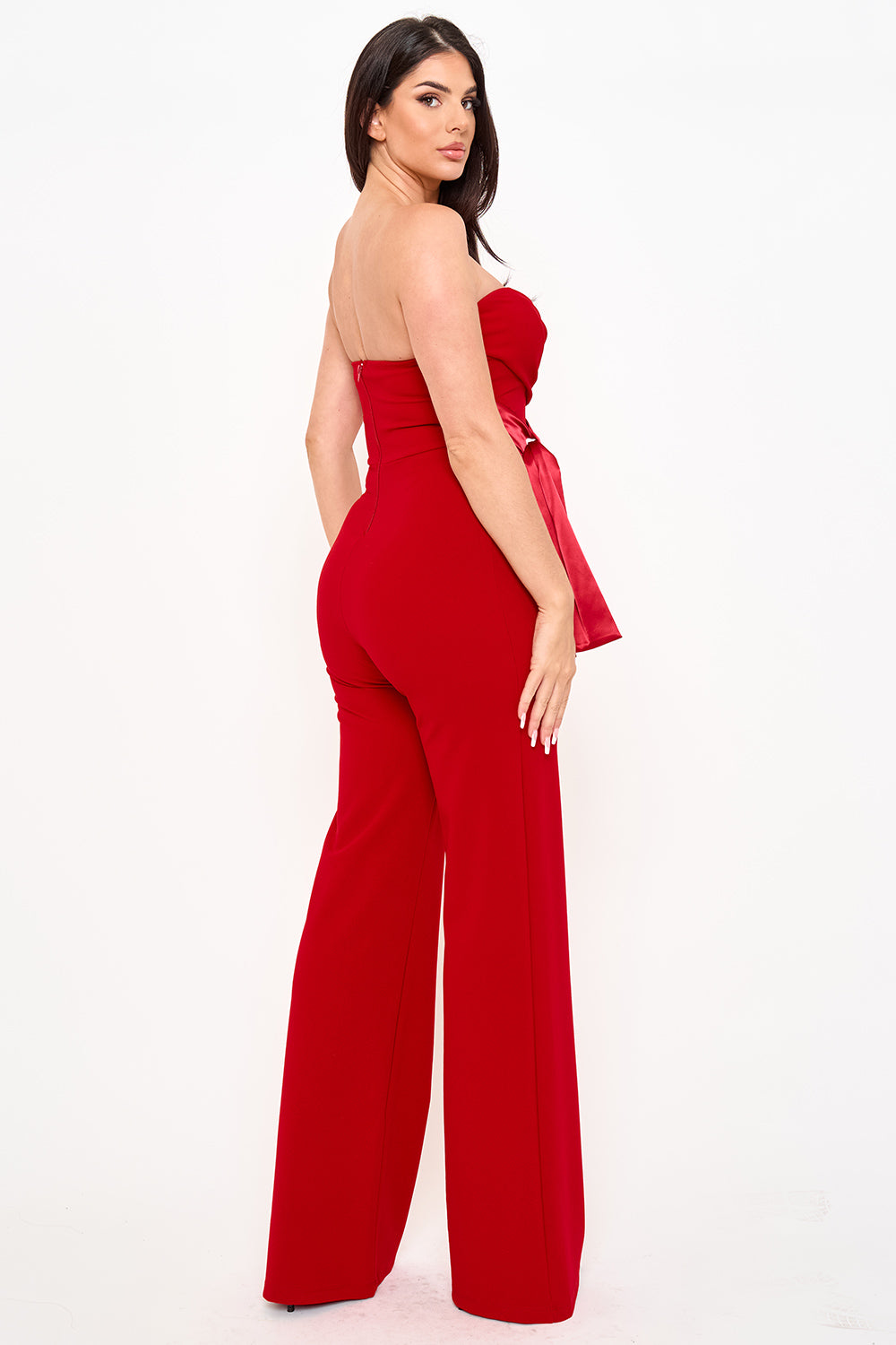 Model wearing a red strapless jumpsuit by Boutinie with a satin bow waist, perfect for formal evening occasions.