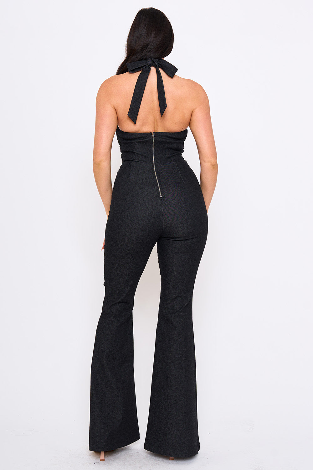 Boutinie black denim halter jumpsuit with a tie-neck back, exposed zipper, and flared legs for a night out.