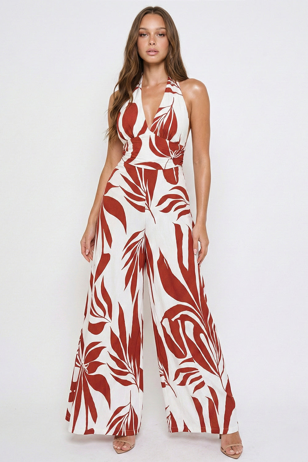 Boutinie rust and white leaf print halter jumpsuit with a plunging neckline and wide-leg silhouette.