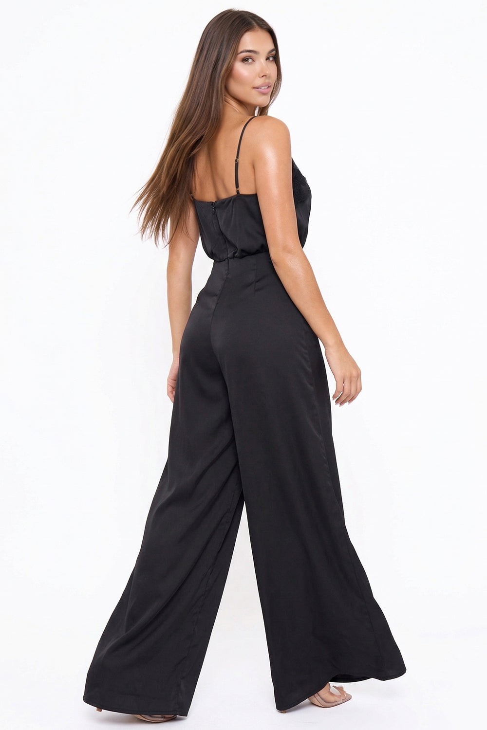 Model wearing a black satin wide-leg jumpsuit with spaghetti straps for an elegant evening look from Boutinie.