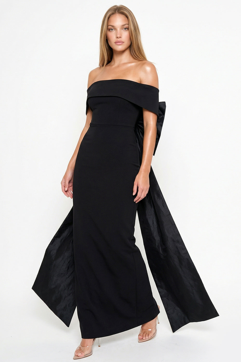 Black off-the-shoulder evening gown with a fitted silhouette, floor-length hem, and a statement back bow detail.