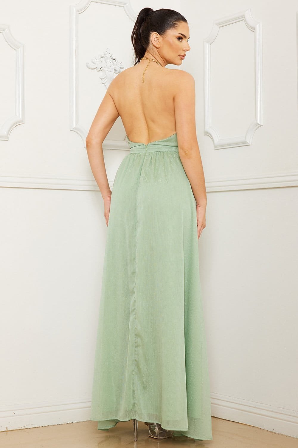 Sage green backless maxi dress with a halter neckline and textured fabric, perfect for formal events at Boutinie.