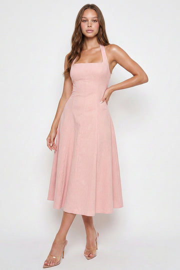 Model wears a blush pink sleeveless midi dress with a square neckline and a flattering A-line silhouette from Boutinie.