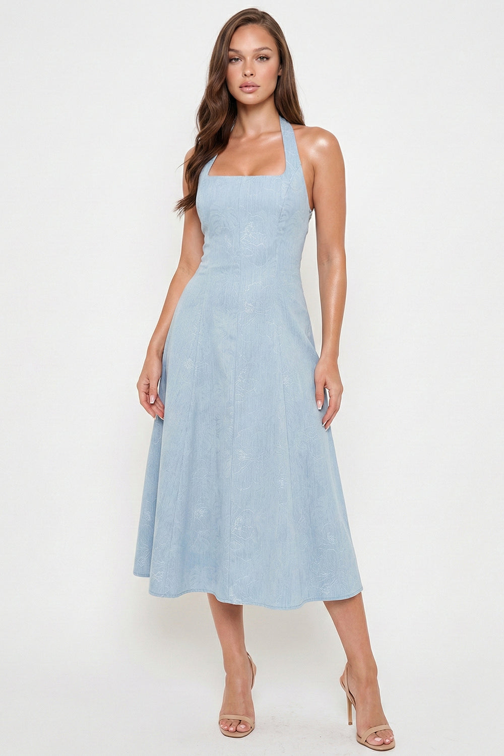 Model wearing a light blue midi dress with a square neckline, halter straps, and subtle floral print by Boutinie.