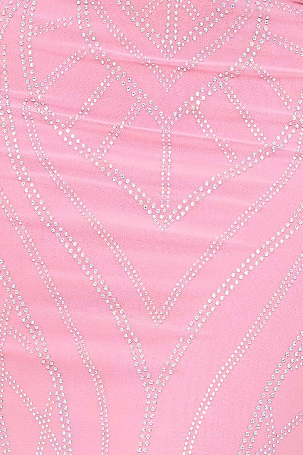 Close-up of a pink party dress fabric featuring intricate geometric patterns detailed with shimmering rhinestones.