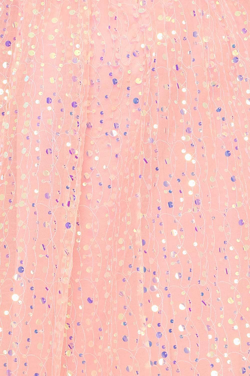 Close-up of a pastel peach tulle party dress fabric featuring delicate iridescent sequins and wavy embroidery detail.