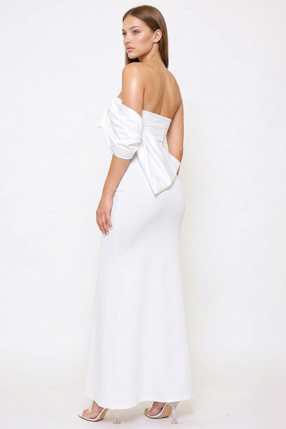 White strapless floor-length evening gown with a statement bow sleeve detail, available at Boutinie.
