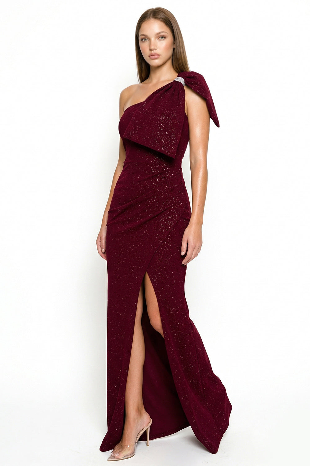 Burgundy glitter one-shoulder maxi gown with a rhinestone shoulder bow and high front slit for formal occasions.