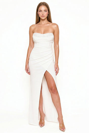 White strapless evening gown with pearl-embellished sweetheart neckline, ruched waist, and high leg slit by Boutinie.