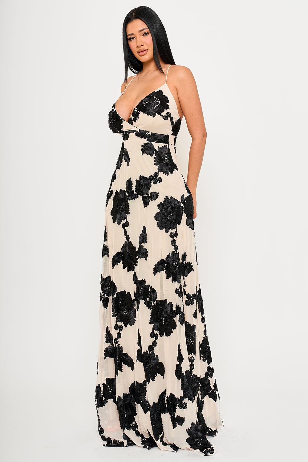 Model wearing a cream V-neck maxi dress with black floral embroidery and thin straps for a formal evening event.
