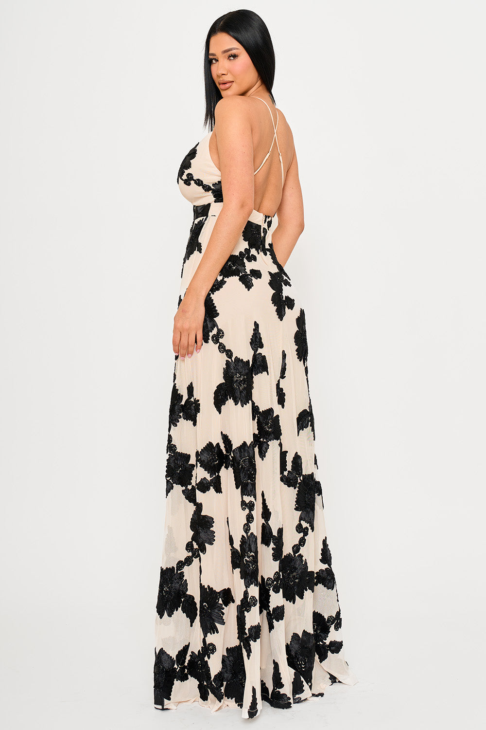 Beige maxi dress with black floral applique, open back, and thin straps, perfect for formal evening occasions.