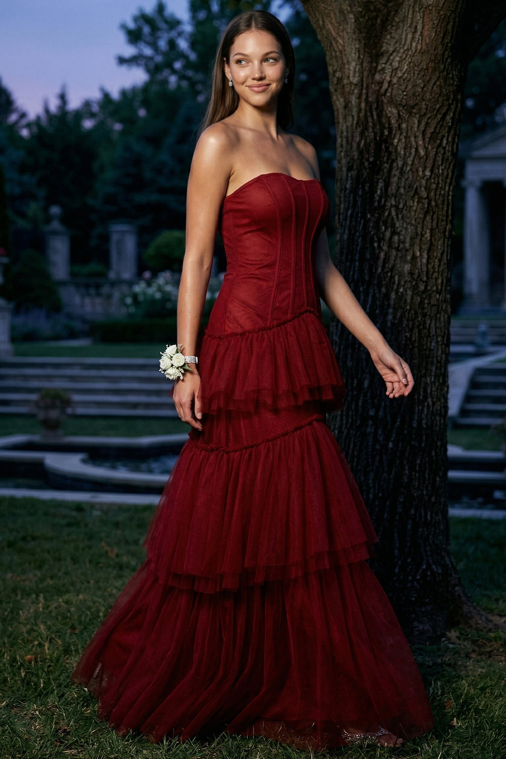 Model wearing a deep red strapless corset-style tulle tiered gown, perfect for prom or formal evening occasions.