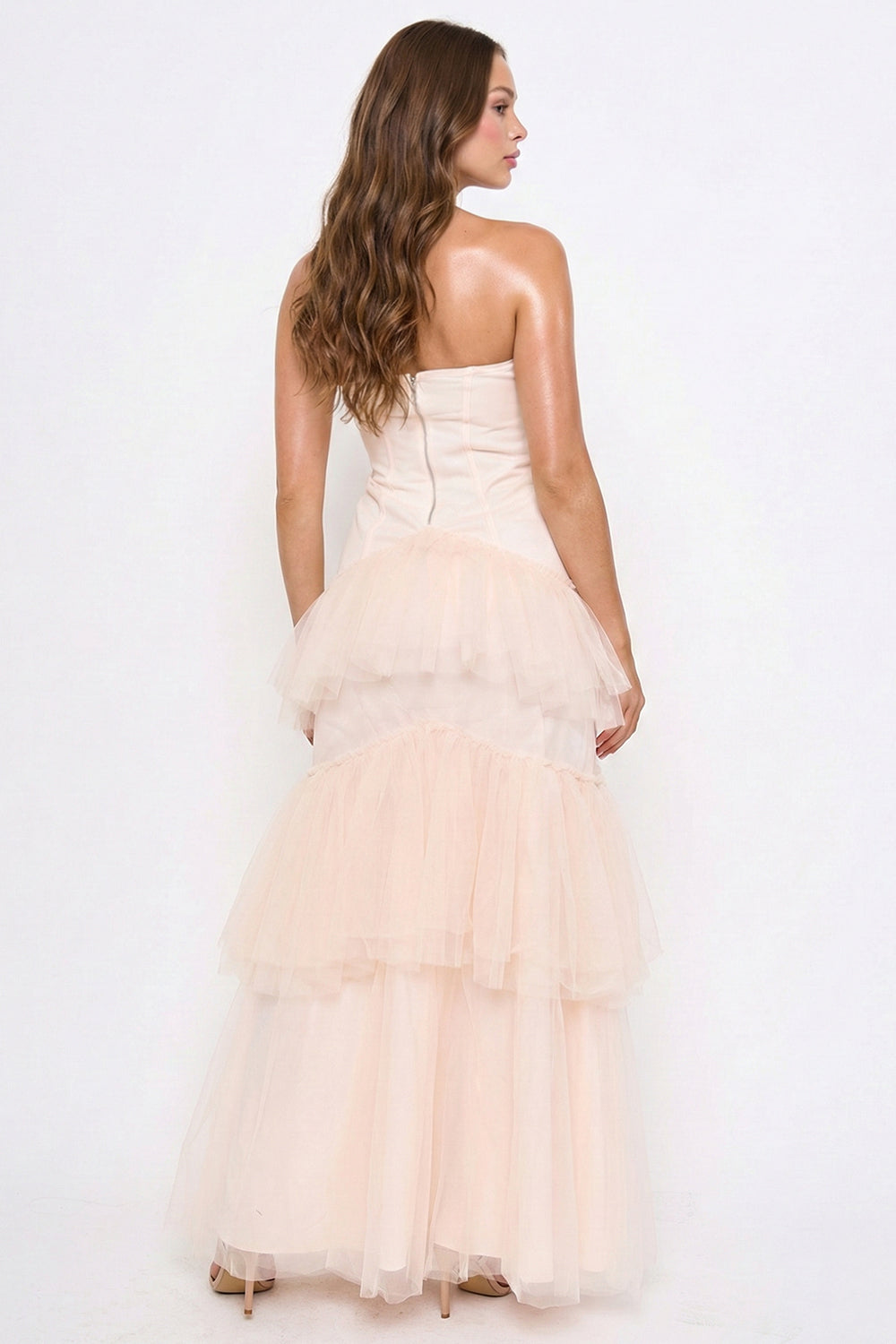 Blush pink strapless corset gown with a tiered tulle skirt, perfect for formal events at Boutinie.