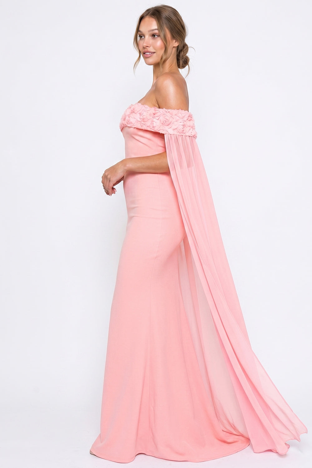 Pink off-the-shoulder formal gown with rosette detailing and flowy chiffon cape sleeves by Boutinie.