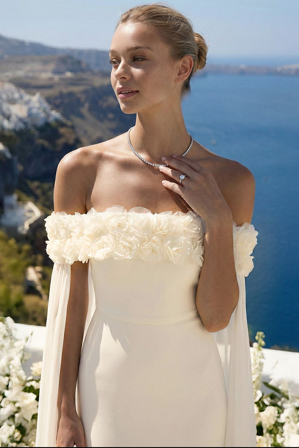 Ivory off-shoulder wedding gown featuring 3D floral neckline detail and flowing cape sleeves by Boutinie.