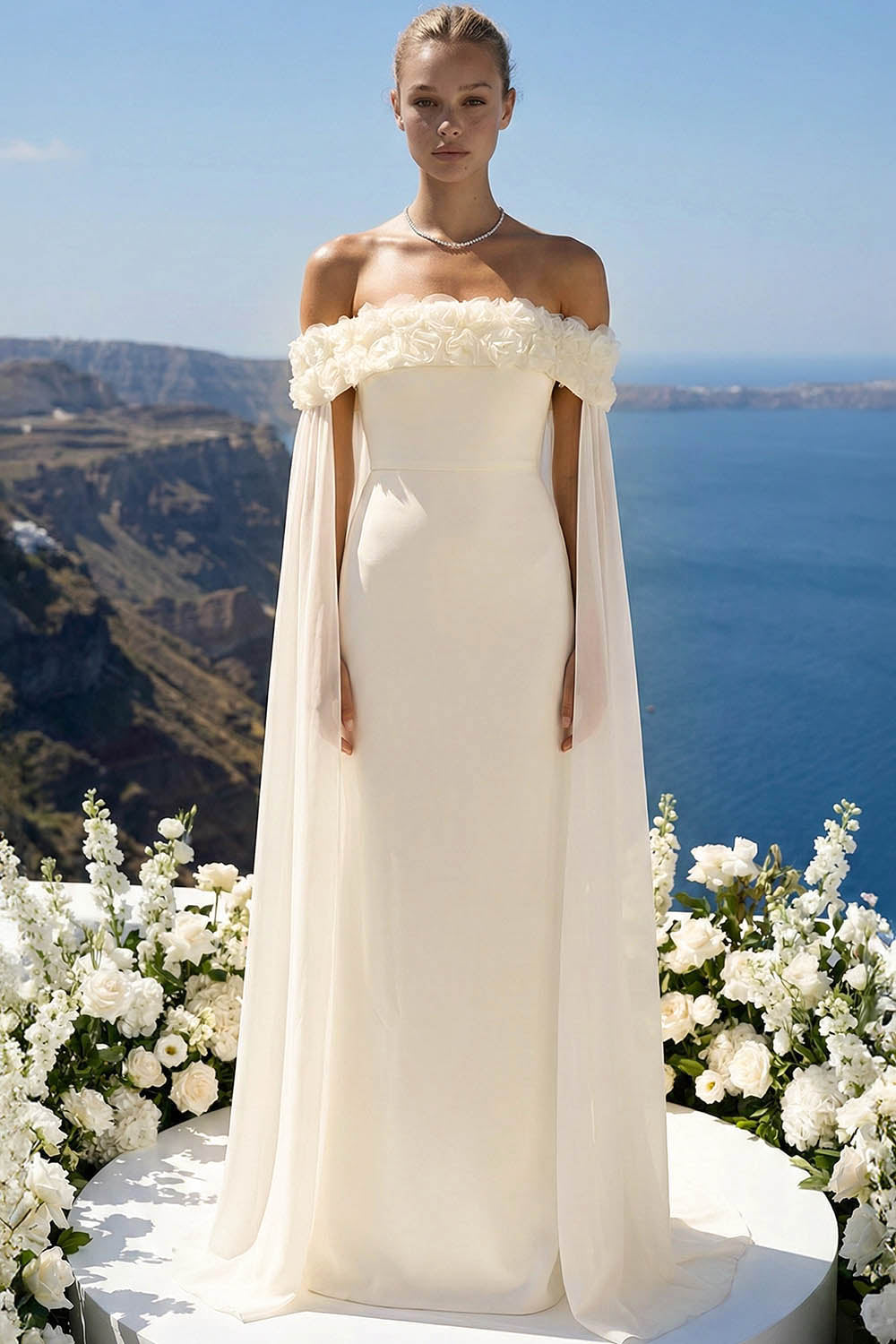 Off-the-shoulder ivory wedding dress with floral neckline and sheer cape sleeves for a romantic bridal look.