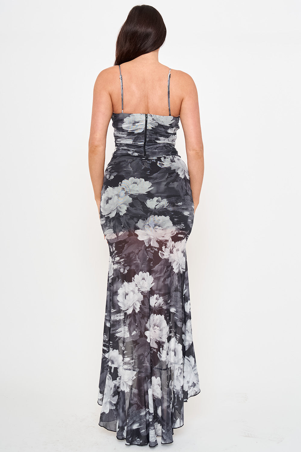 Back view of a black and white floral print maxi gown with a ruched bodice, spaghetti straps, and mermaid silhouette.