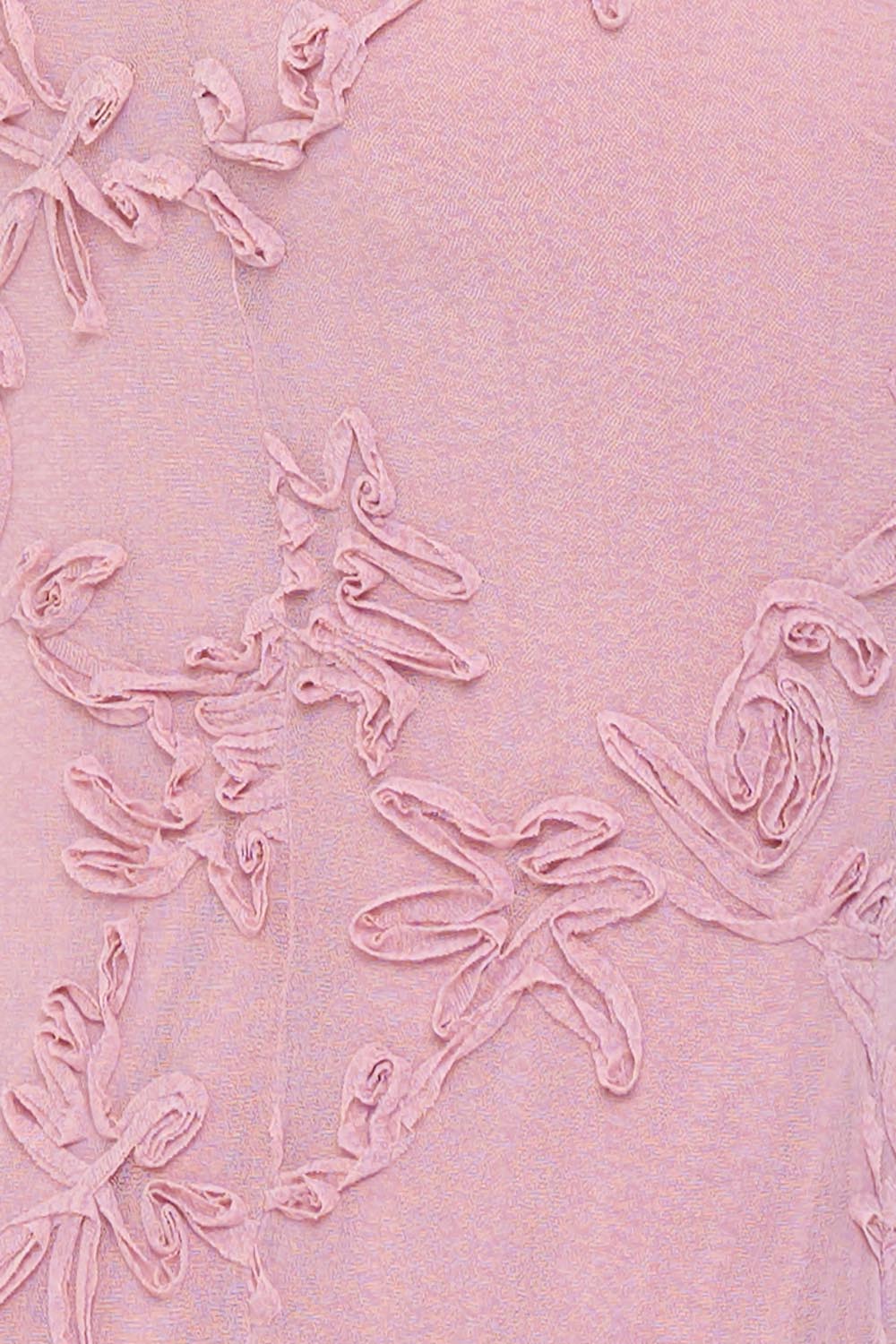 Close-up of a pink textured fabric dress with elegant floral applique details, perfect for special occasions.