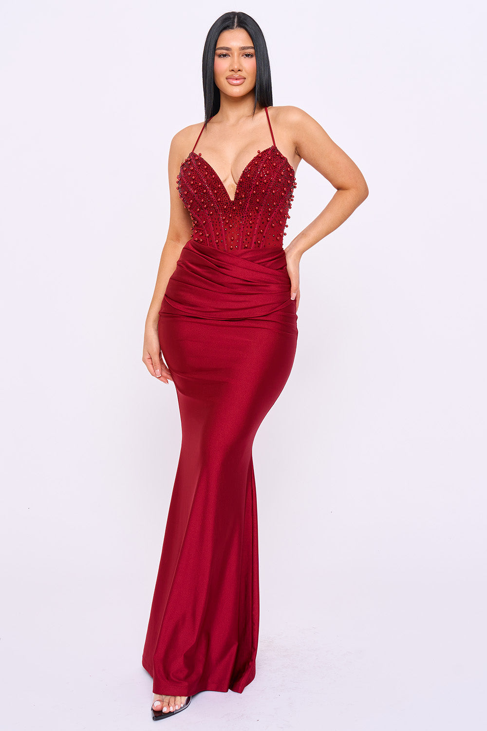 Burgundy beaded corset mermaid evening gown with a deep V-neck and spaghetti straps from Boutinie.